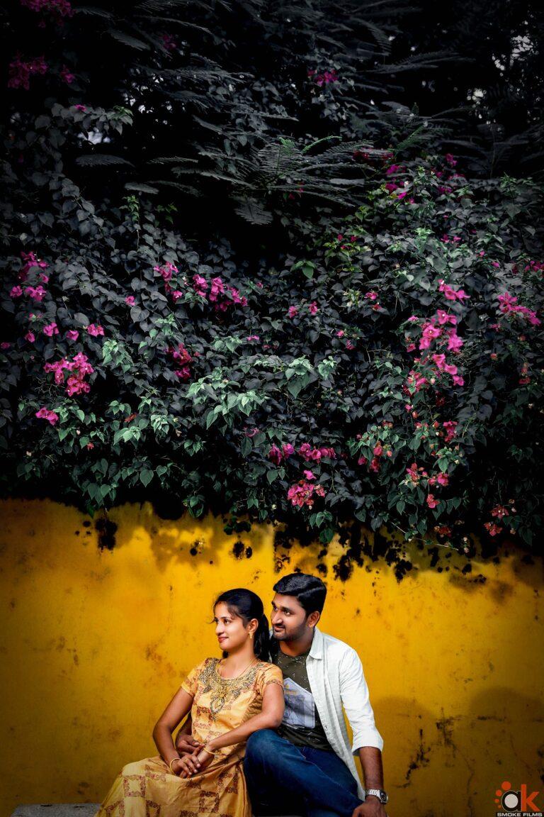With a background of bougainvillea flowers a couple looking on the sides sitting on a stonebench