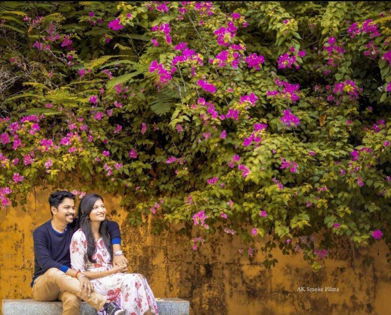 Pink shaded bougainvillea flowers a couple looking on the sides sitting on a stone bench