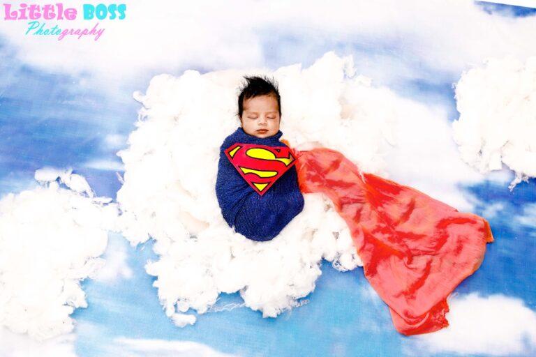 A super man wrap on a newborn baby lying on the cloud background