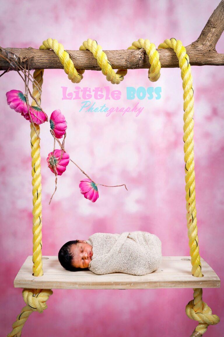new born baby wrapped on a flat wooden swing