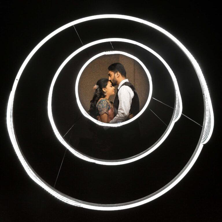 groom kissing bride's forehead inside the a set of white light circles