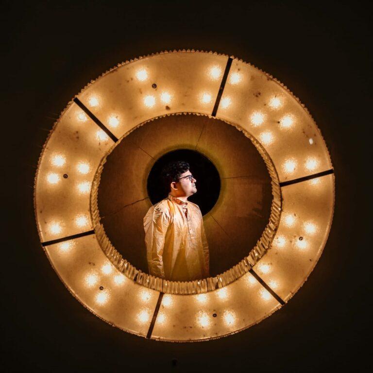 Groom focused inside a golden lights behind a circled fabric screen