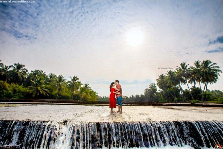 Boy kissing girl's forehead standing in middle of running water with coconut tree on the sides
