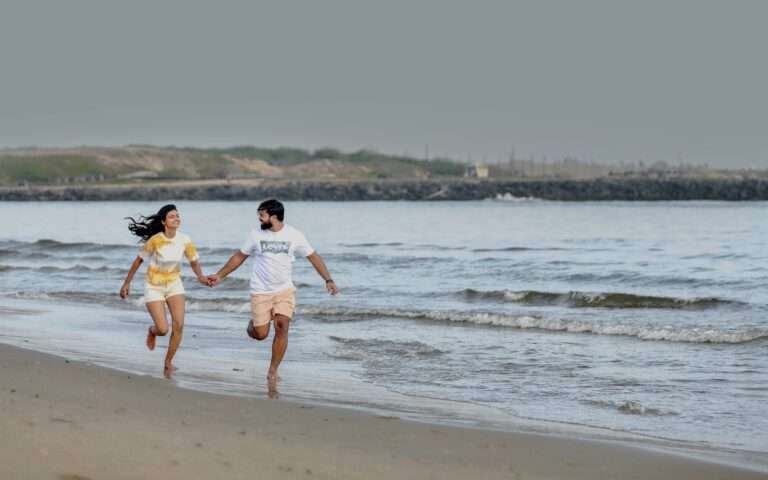 groom and bride running on a seashore holding hands in casual attire
